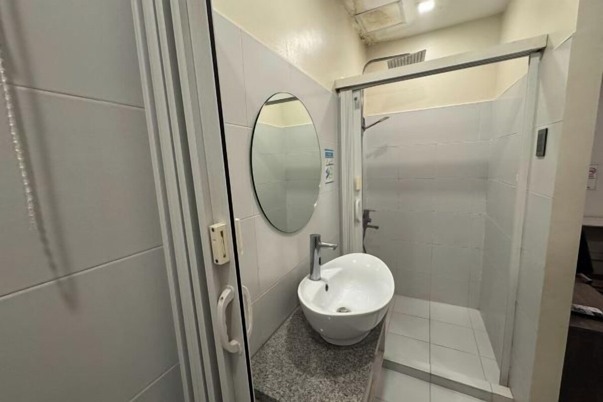 A bathroom with a white sink, a mirror, and a shower area.