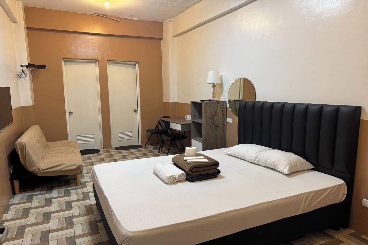 A hotel room with a bed, a desk, and a chair.