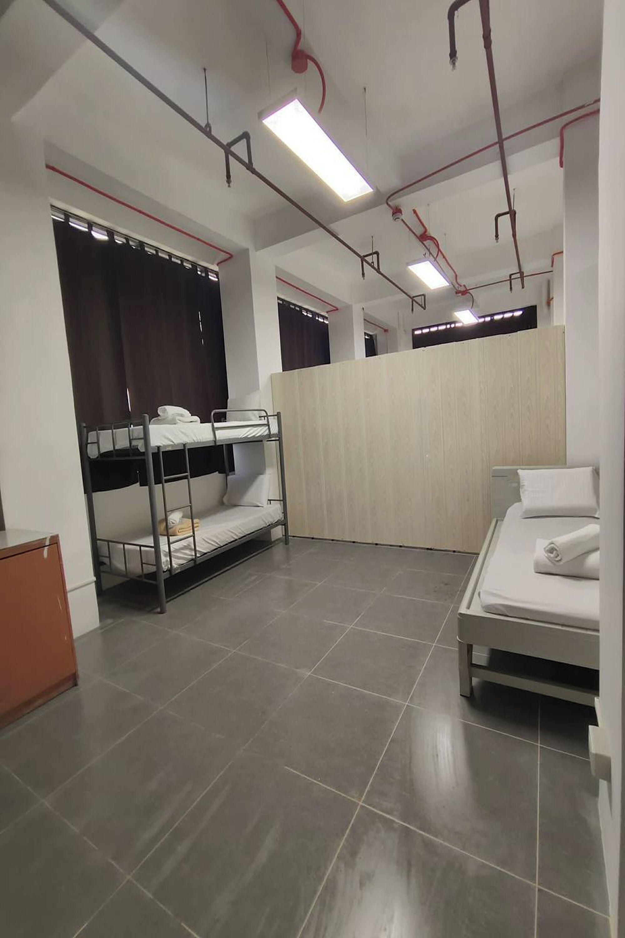 A dormitory room with bunk beds, a single bed, and a wooden partition wall.