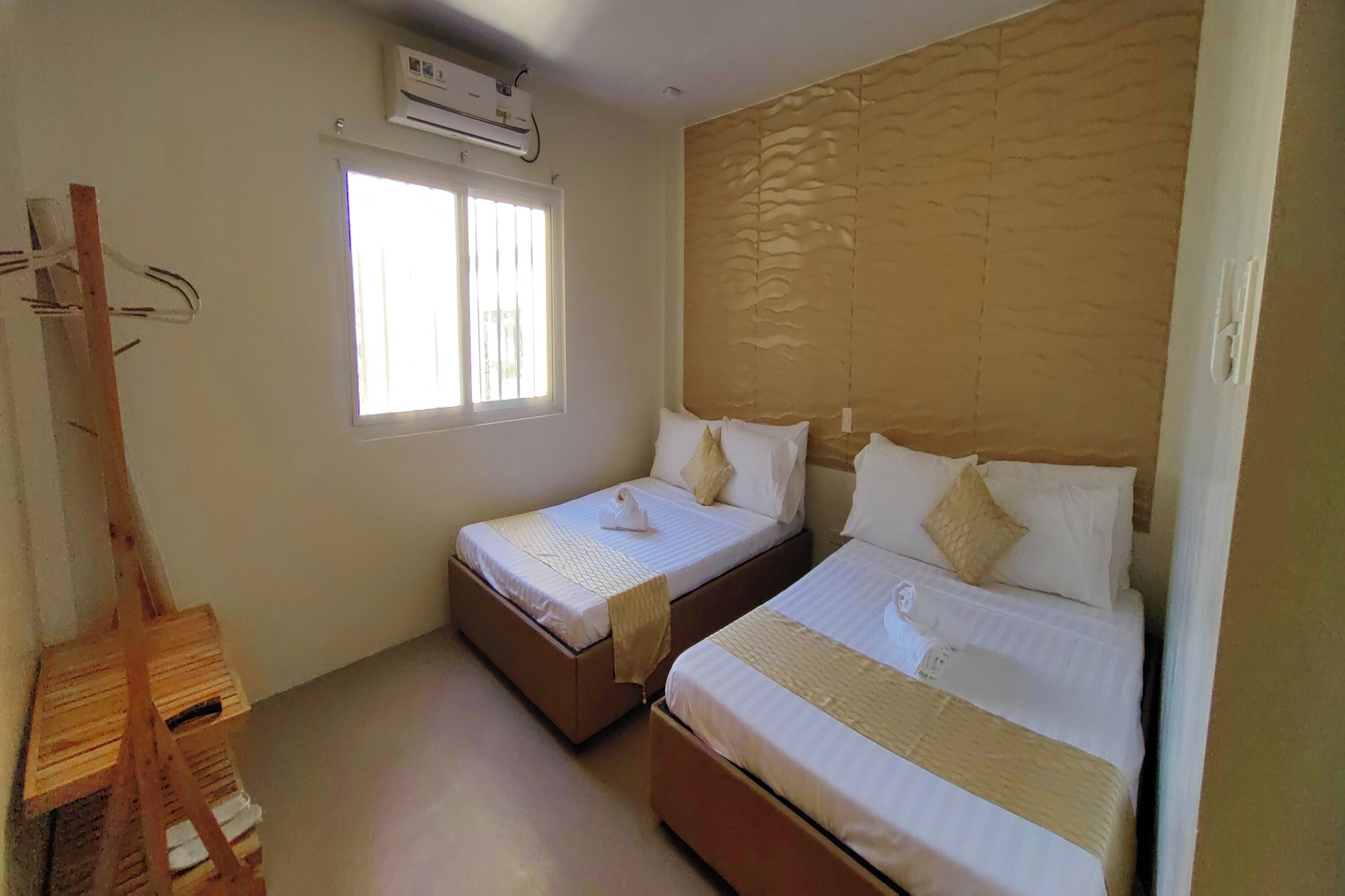 A room with two beds, a window, and an air conditioning unit.