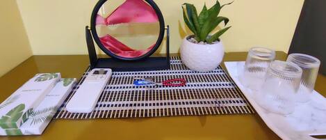 A table with a mirror, a potted plant, a set of keys, a mobile phone, and a tray with glasses.