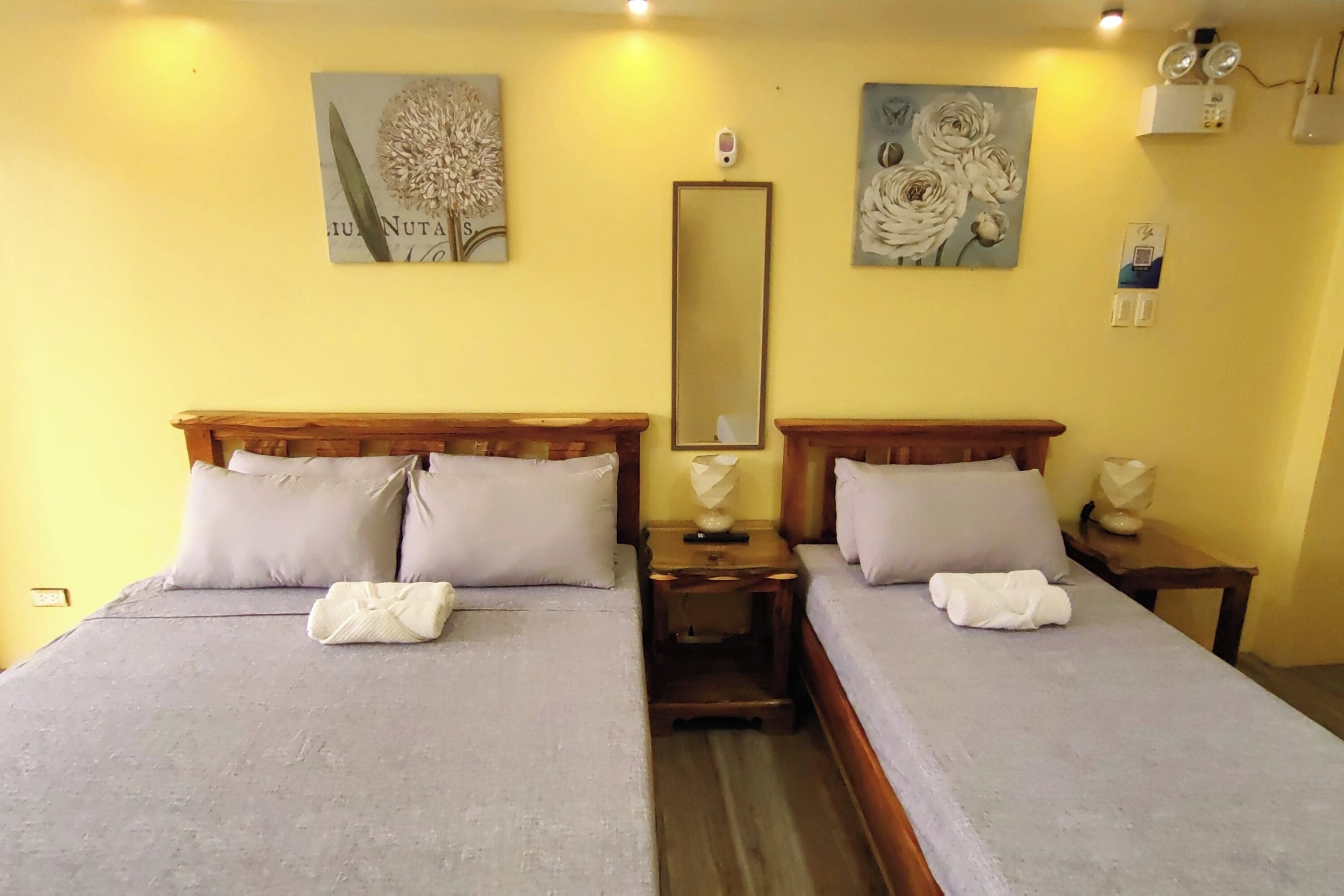 A double bed with two pillows, a nightstand with a lamp, and a mirror on the wall.