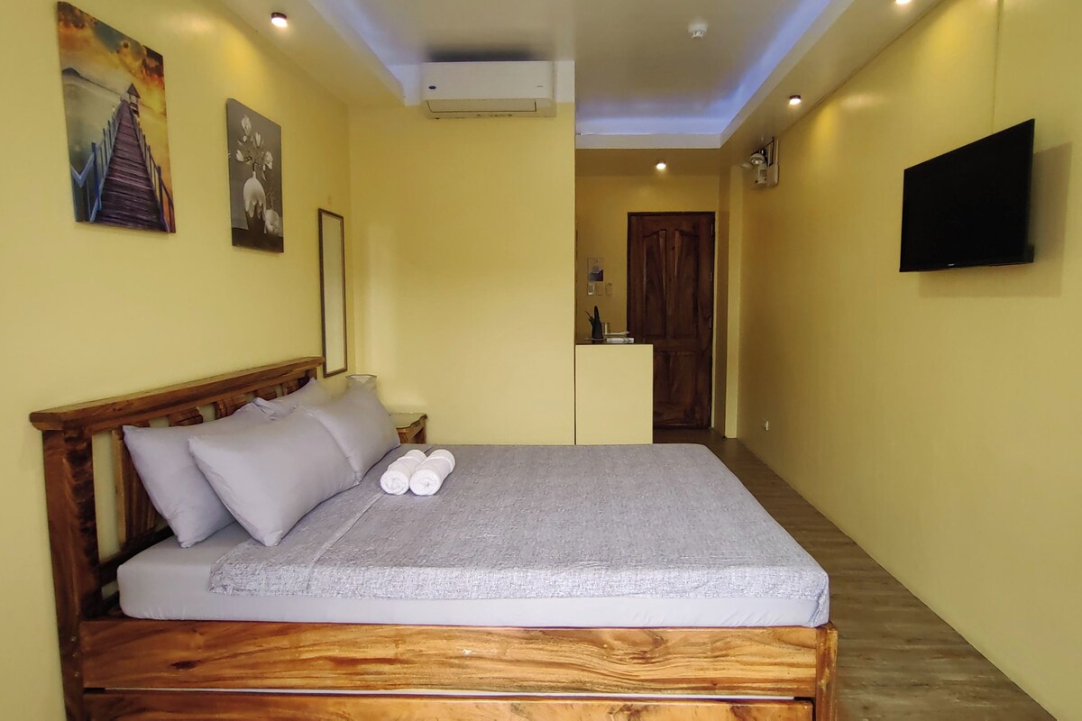 A room with a wooden bed, a flat-screen TV, and artwork on the walls.