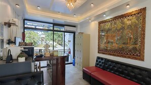 A modern hotel lobby with a reception desk, seating area, and a large decorative painting. - Inn Ka Kay Mame near SM City Puerto Princesa (Puerto Princesa)