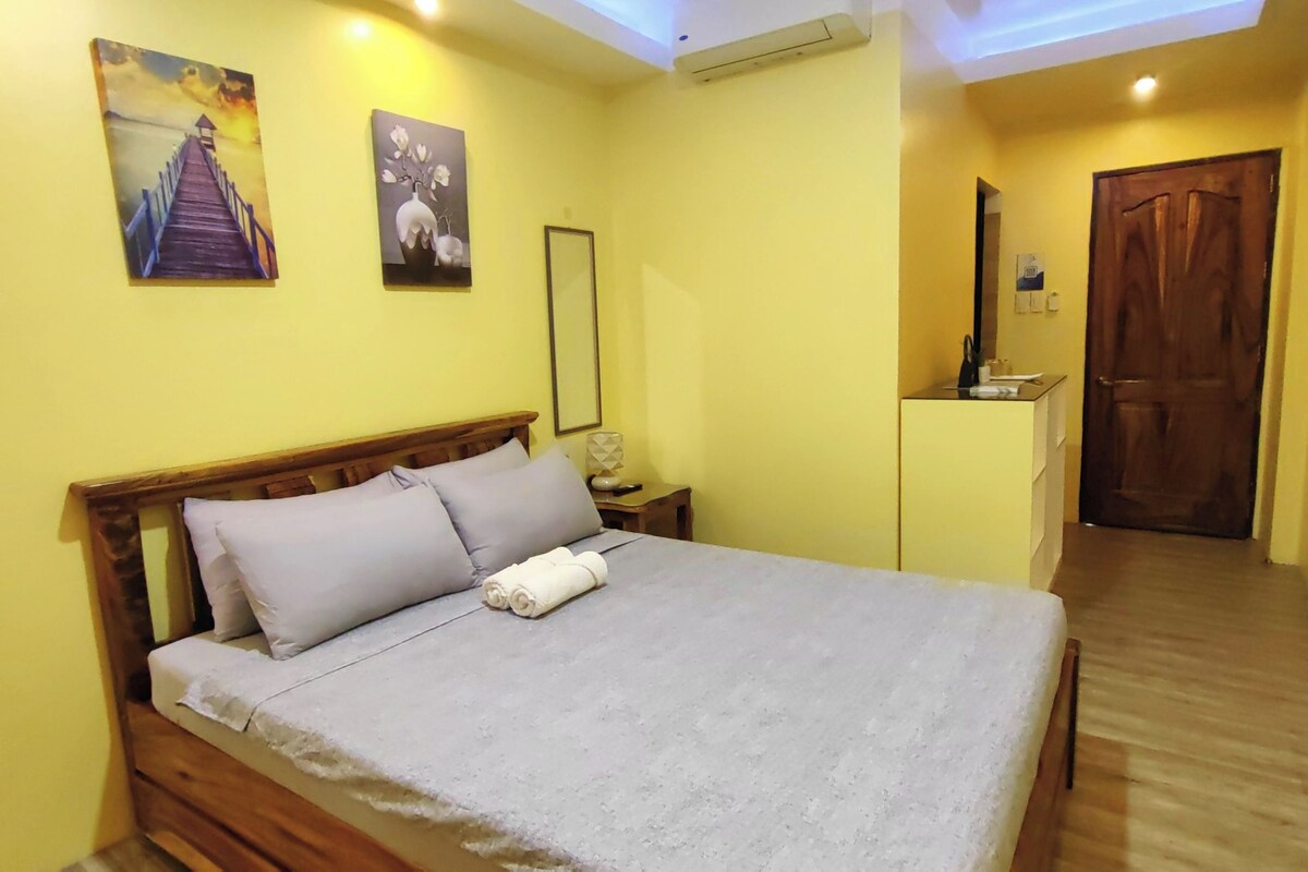 A bedroom with a wooden bed, a nightstand, a mirror, and a door.