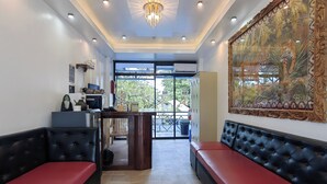A hotel lobby with a reception desk, seating area, and a large decorative painting. - Inn Ka Kay Mame near SM City Puerto Princesa (Puerto Princesa)