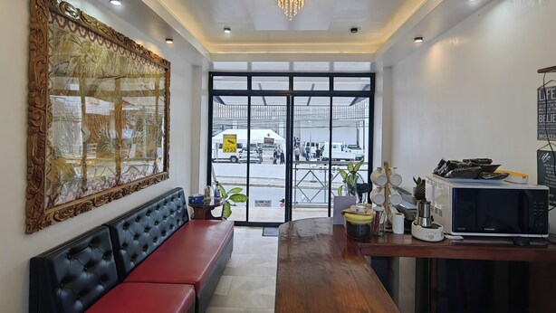 A modern interior with a large window, a chandelier, a seating area, and a kitchen counter with appliances. - Inn Ka Kay Mame near SM City Puerto Princesa (Puerto Princesa)