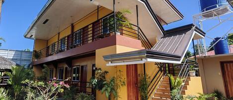 A two-story house with a balcony, a staircase, and a water tank.