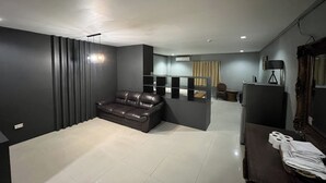 Un salon moderne avec un canapé en cuir foncé, une table basse en verre et une petite table d’appoint sur laquelle sont posées des serviettes.