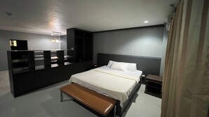 Une chambre moderne avec un grand lit, un banc, une table de chevet et une armoire.