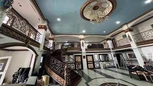 Un intérieur somptueux avec un escalier central, des rampes décoratives et un lustre.