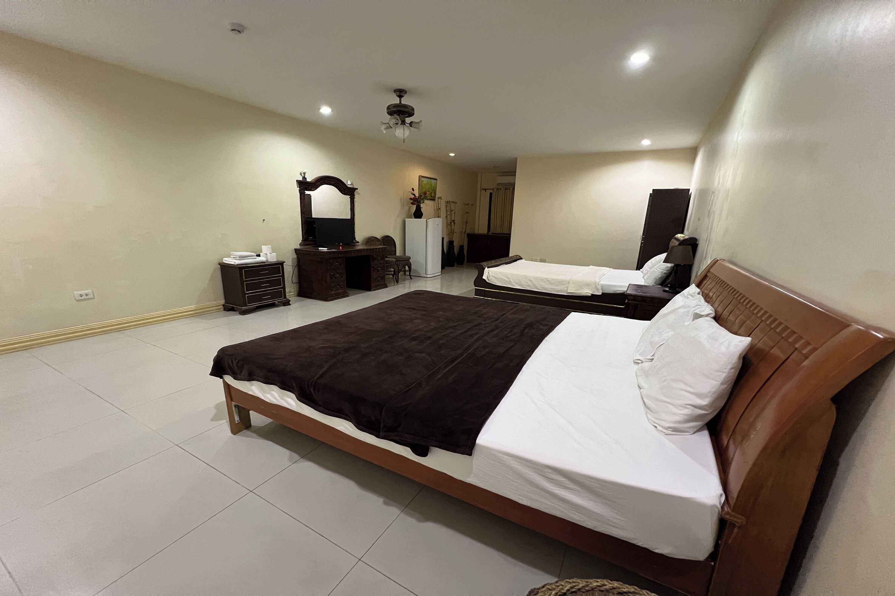 Una habitación de hotel con una cama grande, un aparador, un espejo, un escritorio y una silla.