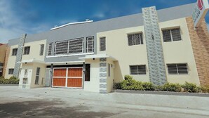 A modern two-story building with a garage, large windows, and a sign indicating a business or commercial use. - Ljenj Apartelle (Mabalacat City)