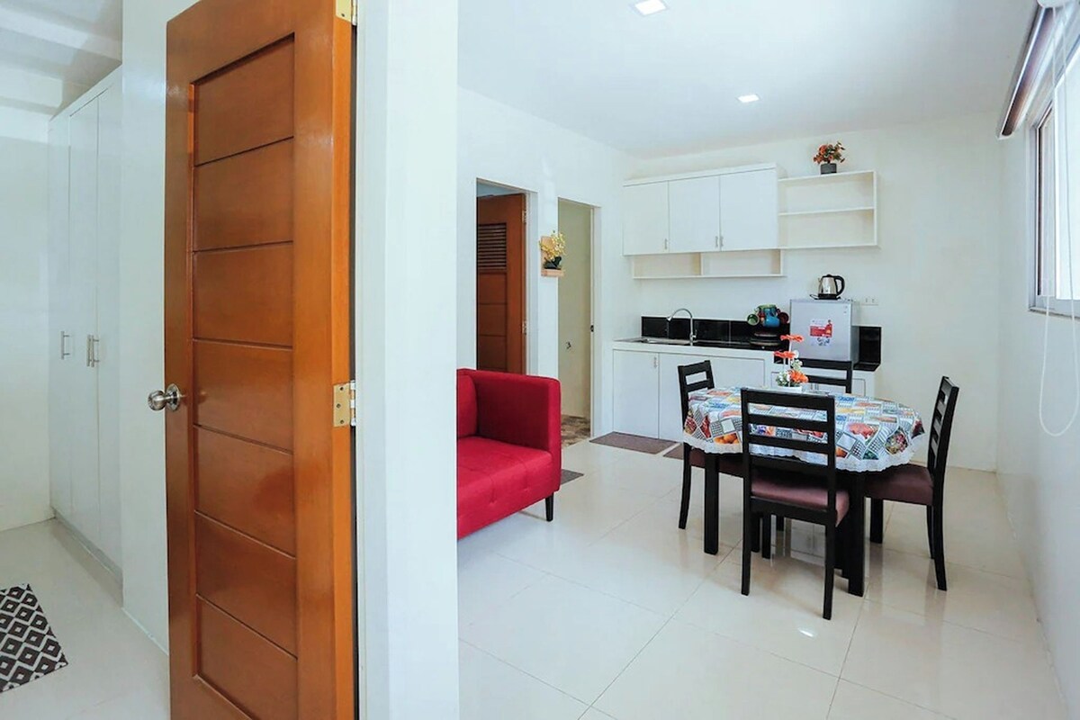 A compact living space with a dining area, kitchenette, and a red sofa.