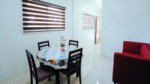 A dining area with a table, chairs, and a red sofa. - Ljenj Apartelle (Mabalacat City)