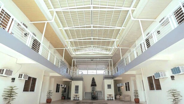 A spacious indoor area with a high ceiling, multiple air conditioning units, and potted plants. - Ljenj Apartelle (Mabalacat City)