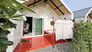 A modern house with a red wooden deck, a sliding glass door, and a hanging light fixture.