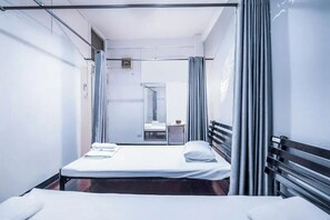 A single-bed room with a metal frame, a small table with a chair, and a window with curtains. - Ali Hostel (Bangkok)