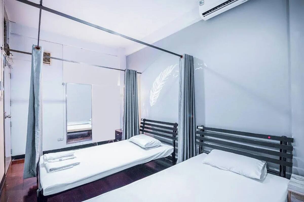 A hotel room with two beds, a large mirror, and a window with curtains.