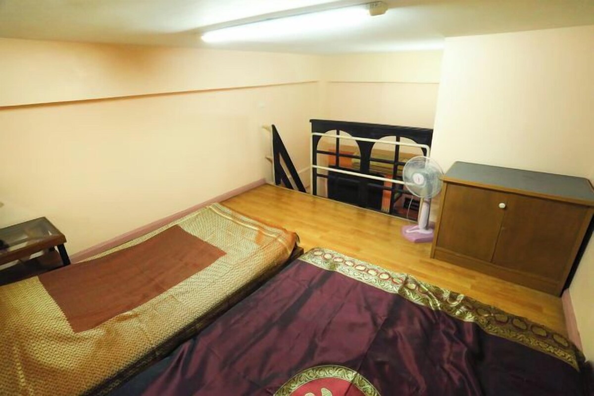 A small, compact room with a single bed, a wooden cabinet, and a desk.