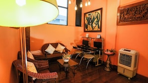 A cozy living area with a sofa, chairs, a coffee table, a lamp, a TV, and a heater. - Pjr Chateau (Bangkok)