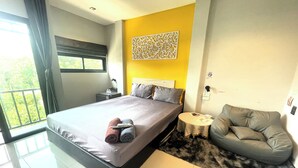 A modern bedroom with a large bed, a small round table, and a grey sofa. - Baan Pak Sud Soi (Si Racha)