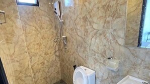 A bathroom with a marble wall, a toilet, a sink, and a shower. - Baan Pak Sud Soi (Si Racha)