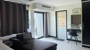 A modern hotel room with a bed, a desk, and a chair. There is a sliding door leading to a balcony. - Bkl Pool Villa Pattaya (Bang Lamung)