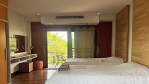A modern hotel room with a large bed, a TV on a wooden shelf, and a balcony with a view of trees and flowers. - Bkl Pool Villa Pattaya (Bang Lamung)