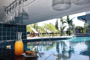 Um bar à beira da piscina, com um copo de sumo de laranja e uma taça de petiscos.