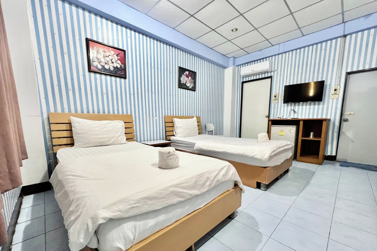 A hotel room with two beds, a TV, and a mirror.