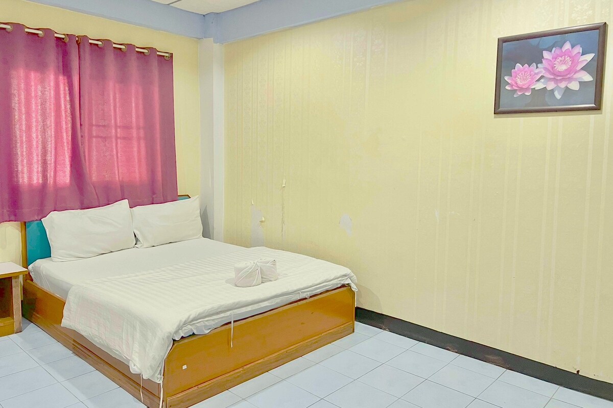 A bedroom with a bed, curtains, a wall-mounted picture, and a tiled floor.
