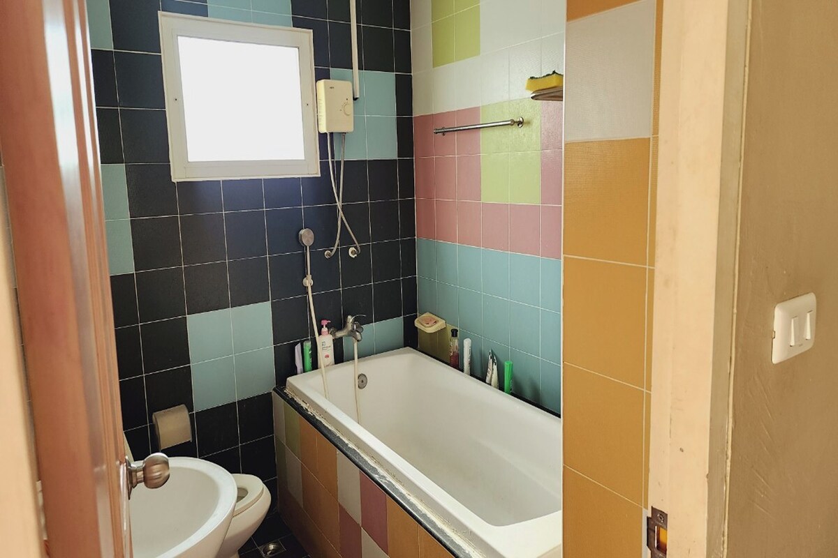 A bathroom with a bathtub, toilet, and a window above the toilet.
