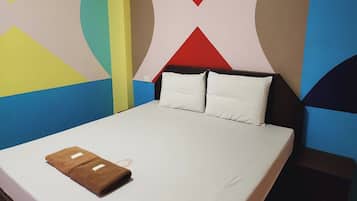 Ein Bett mit weißer Bettwäsche, zwei Kissen und ein braunes Handtuch.