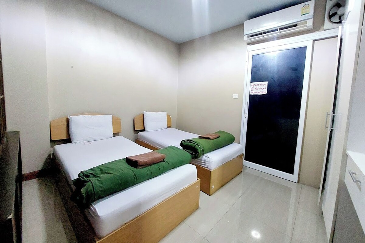 Une chambre d’hôtel avec deux lits, une armoire et un appareil de climatisation.