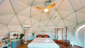 A spacious tent with a bed, a ceiling fan, and a small table with a plant. - Nanine Glamping By Zuzu (Cha-am)