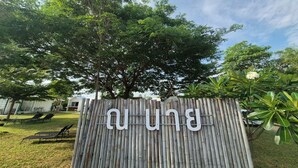 A bamboo fence with the word "BUN" in white letters, a tree, and a lawn with lounge chairs. - Nanine Glamping By Zuzu (Cha-am)