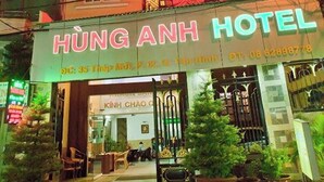 A hotel entrance with a sign reading "HUNG ANH HOTEL" and a contact number. There are potted plants and a gated entrance visible. - Hung Anh Hotel (Ho Chi Minh City)