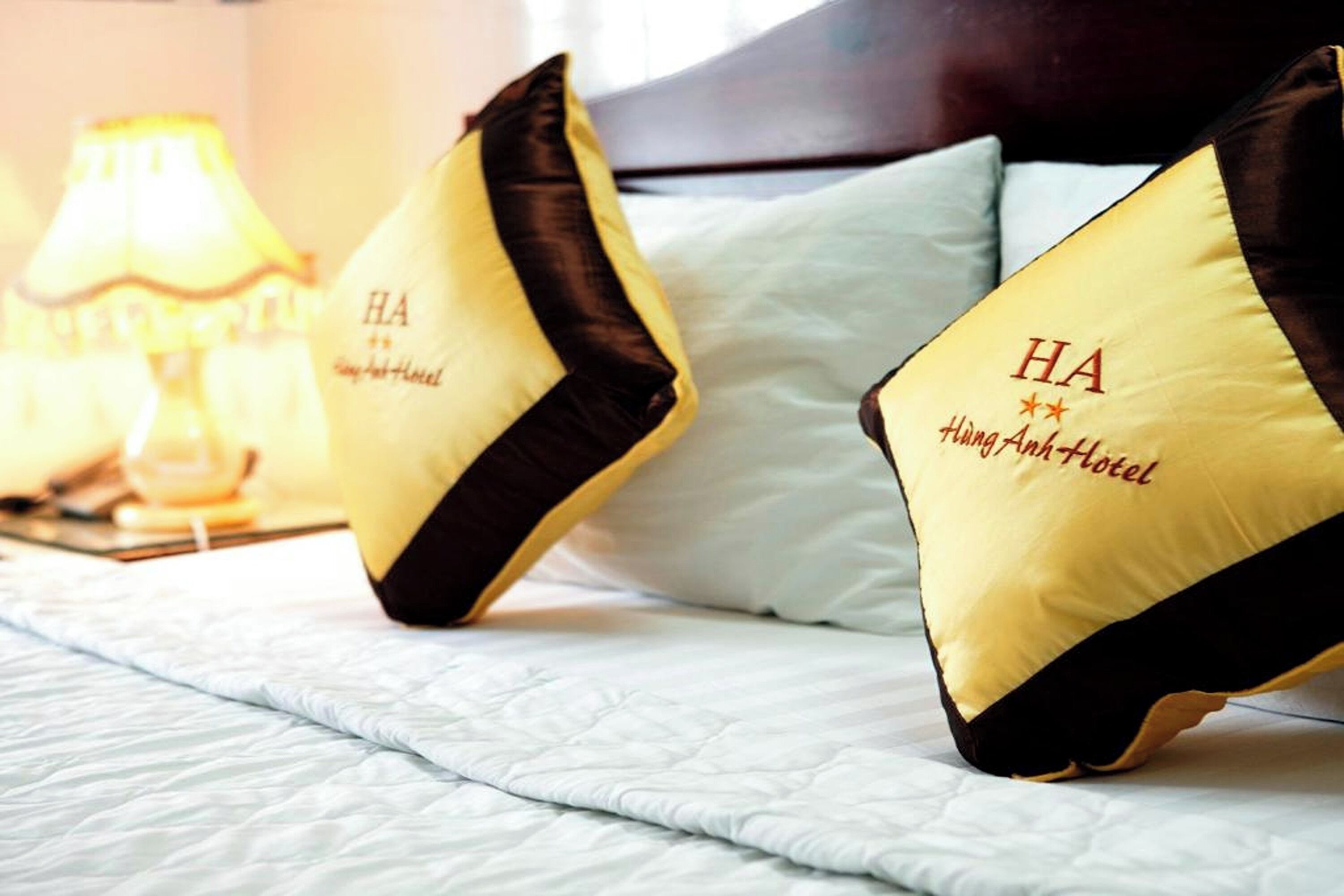 A bed with two pillows, each labeled "HA Hangi Anholt Hotel."