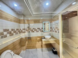 Um banheiro moderno com chuveiro em box de vidro, um lavatório com pia e vaso sanitário.