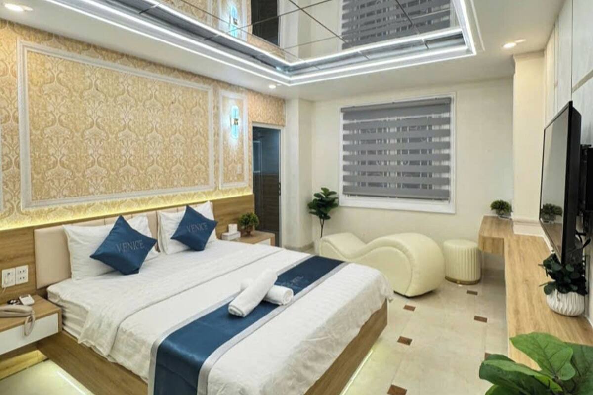 Una habitación de hotel moderna con una cama grande, televisión y ventana con persianas.