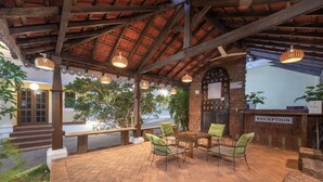 A reception area with a brick floor, wooden tables and chairs, hanging wicker lamps, and a brick wall with a 'RECEPTION' sign. - Echor Avontade Pool Villas Anjuna Goa (Anjuna)