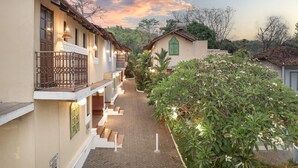 A hotel with a brick pathway leading to the entrance, surrounded by lush greenery and a clear sky. - Echor Avontade Pool Villas Anjuna Goa (Anjuna)