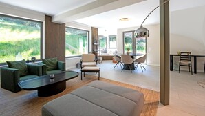 A modern living room with a sofa, coffee table, and dining area. - Luxury Chalet in Niederau With Whirlpool (Hopfgarten im Brixental)