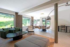 A modern living room with a sofa, coffee table, and dining area. - Luxury Chalet in Niederau With Whirlpool (Hopfgarten im Brixental)