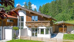 A modern two-story house with a balcony, a wooden fence, and a garden. - Luxury Chalet in Niederau With Whirlpool (Hopfgarten im Brixental)