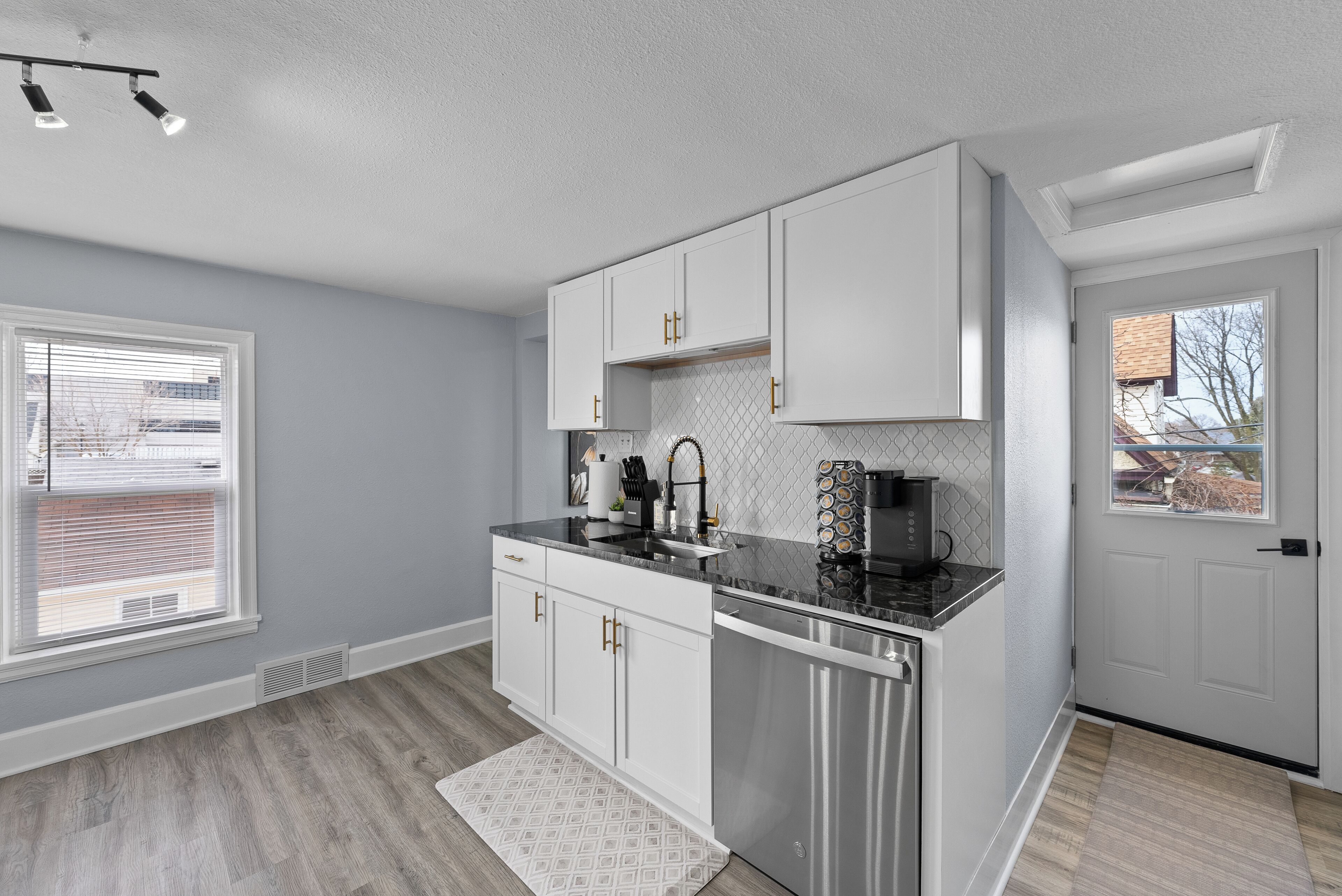 A modern kitchen with white cabinets, stainless steel appliances, and a black countertop.