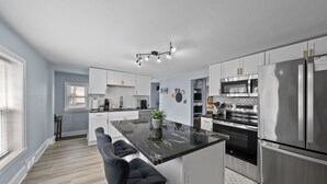 Une cuisine moderne dotée d’un îlot central, d’appareils électroménagers en acier inoxydable et d’un coin bar.