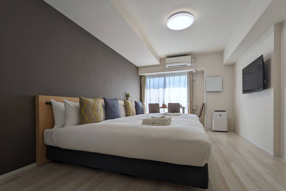 Une chambre d’hôtel moderne équipée d’un grand lit, d’un téléviseur à écran plat et de la climatisation.