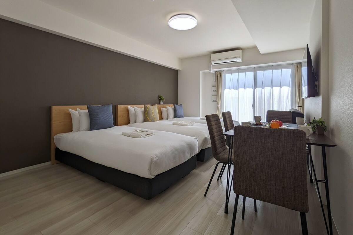 Une chambre d’hôtel avec deux lits, un coin repas et un téléviseur.